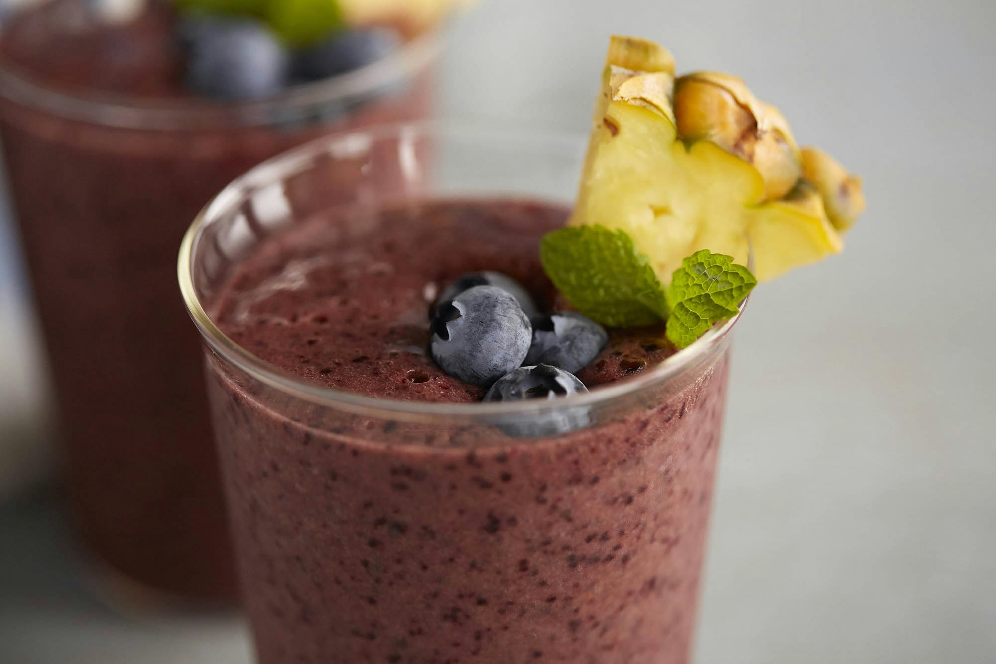 Two glasses of blueberry kale and pineapple smoothie 