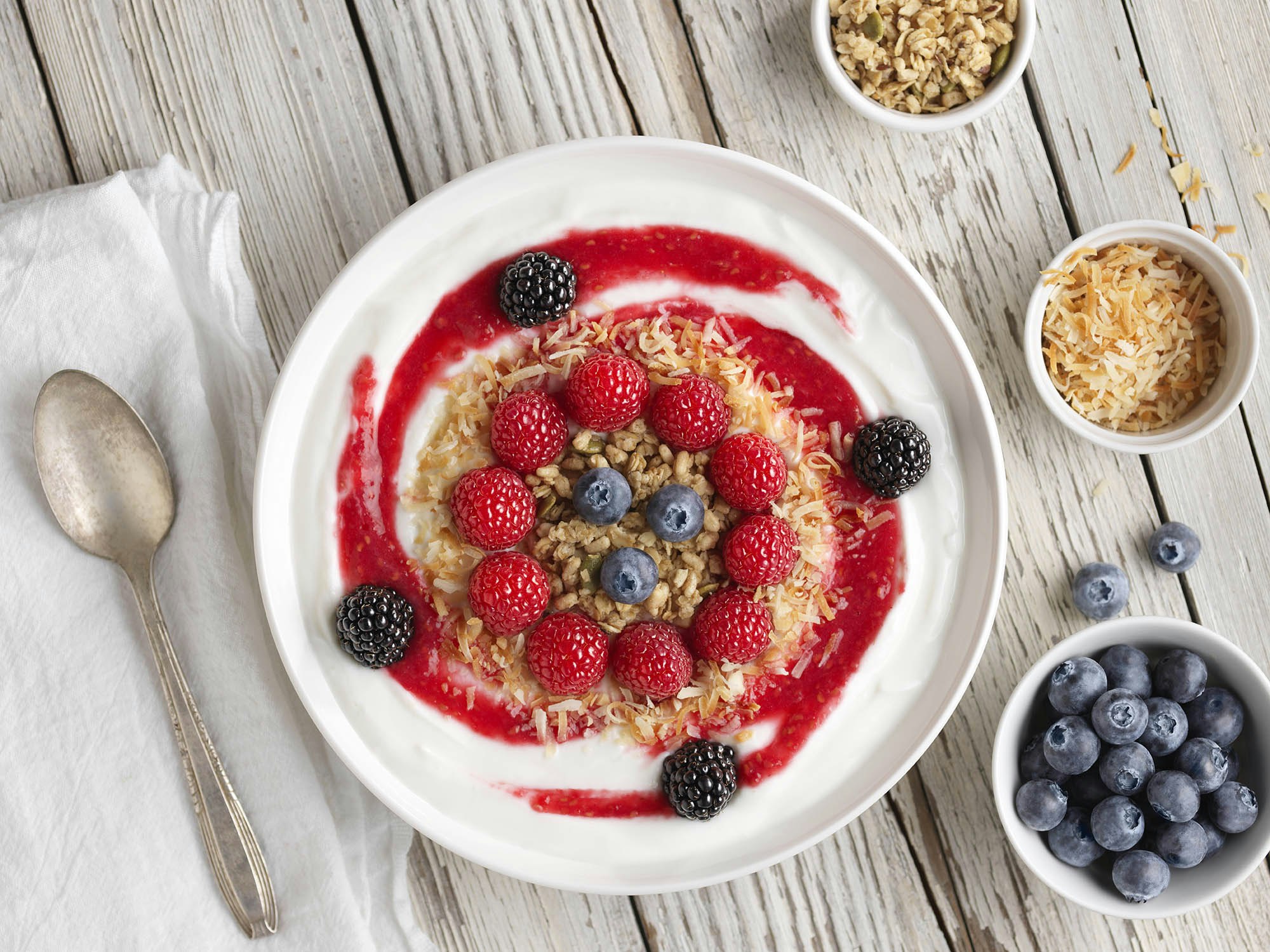 Raspberry smoothie bowl with decorative design and a bowl of blueberries